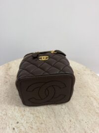 Chanel Vanity Mini brown quilted bag with gold zipper on table.