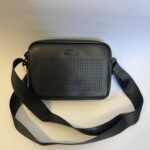 Black Lacoste bag with perforated design and strap.