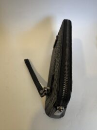 Bottega Veneta black clutch with woven texture and zipper detail.