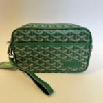 Green Goyard crossbody bag with signature pattern and wrist strap.